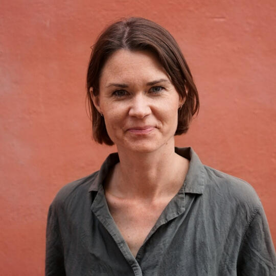 Profilfoto af psykologen, orange baggrund.